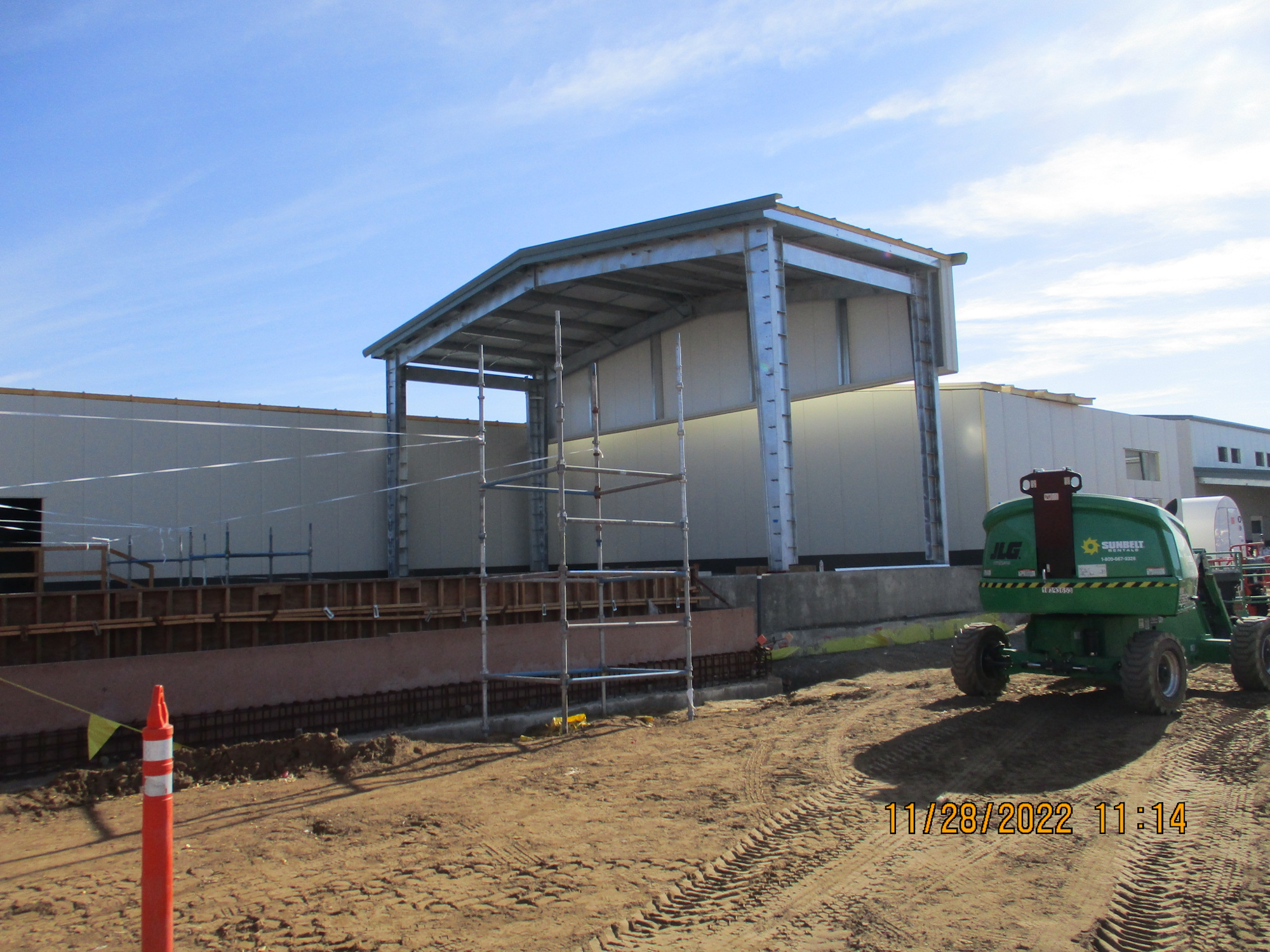 Construction site with partially built structure, scaffolding, and a scissor lift.