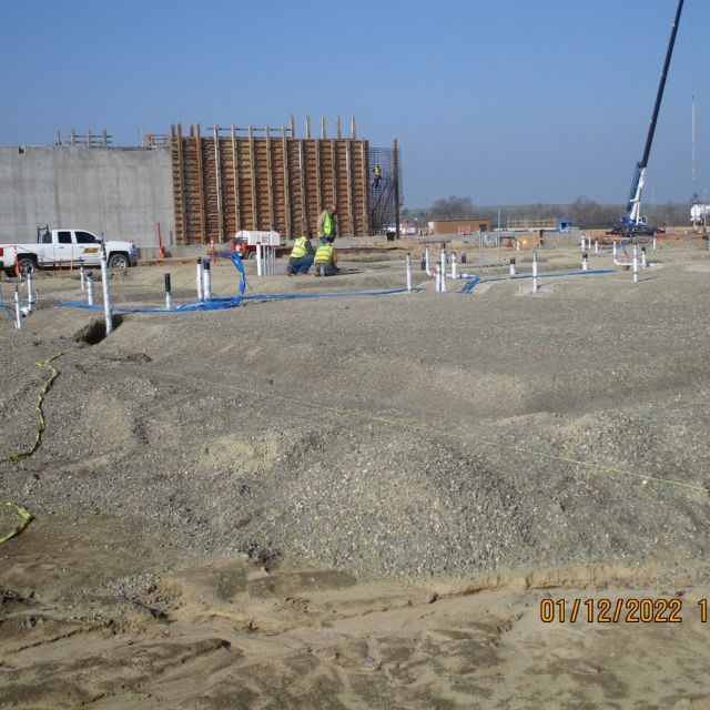 Construction site with workers, formwork, and groundwork in progress.