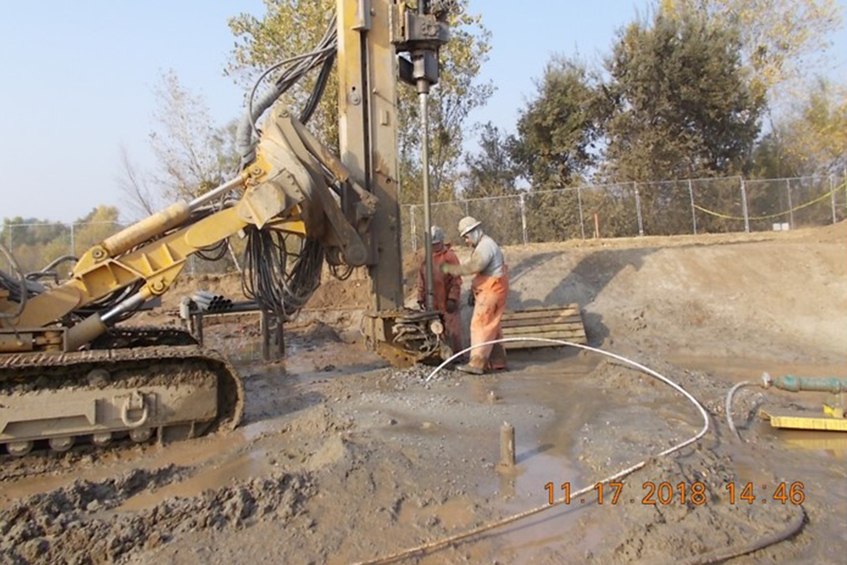 Drilling rig and workers on a muddy construction site.