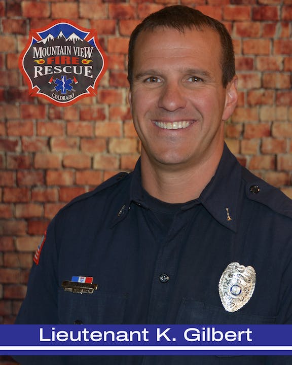 A smiling firefighter with insignia, labeled "Lieutenant K. Gilbert," against a brick wall backdrop with a Mountain View Fire Rescue logo.