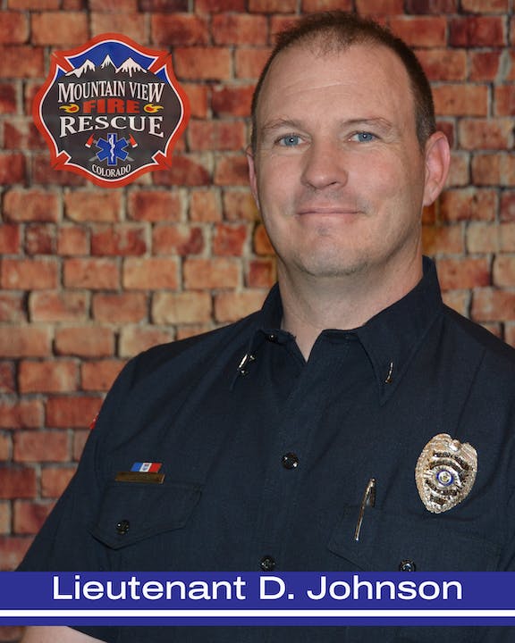 A firefighter in uniform with a badge, standing in front of a brick wall, with an emblem captioned "Mountain View Fire Rescue Colorado".