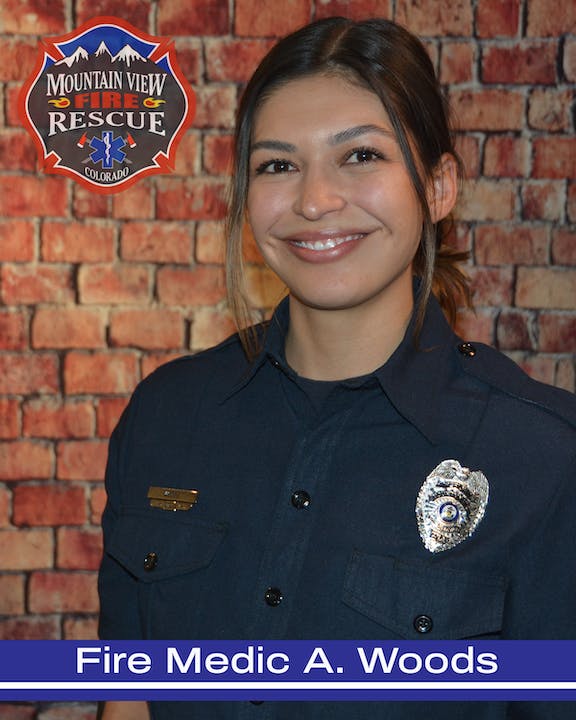 A smiling person in a uniform with a badge labeled "Mountain View Fire Rescue Colorado", with the name "Fire Medic A. Woods".