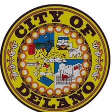 Seal of the City of Delano, featuring fruits, buildings, and industrial elements on a yellow background.