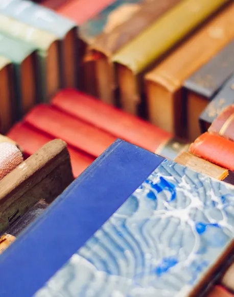 A close-up of a collection of colorful, aged book spines lined up on a shelf.