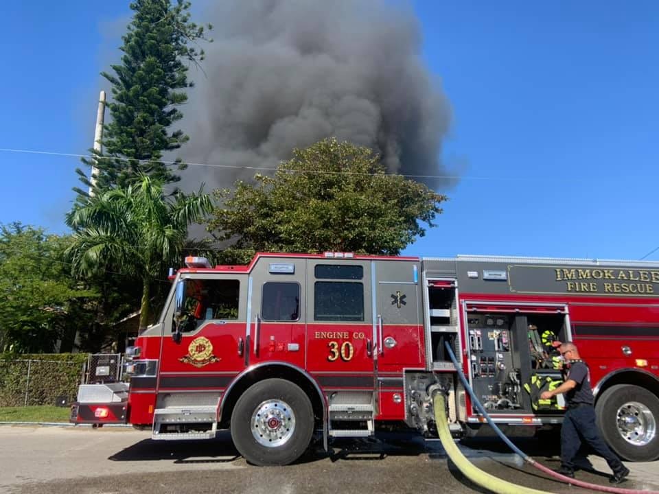 Fire truck and firefighter responding to a fire, with smoke rising in the background.