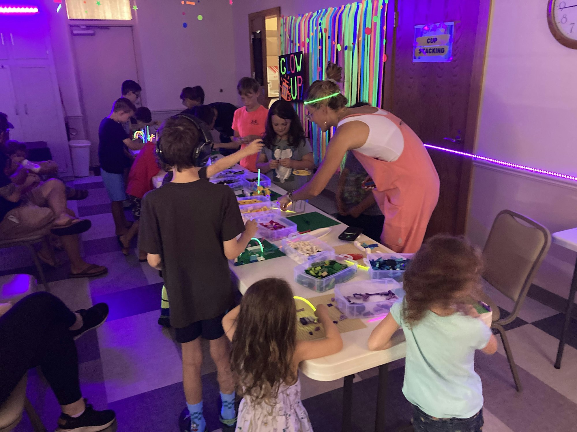 Kids building with blocks under blacklight at a glow-themed event.