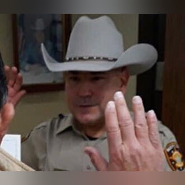 A person wearing a cowboy hat and tan shirt visible in a cropped indoor photo.