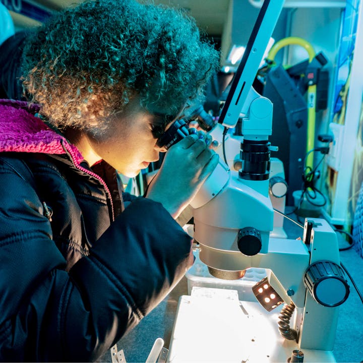 Female student looking through microscope