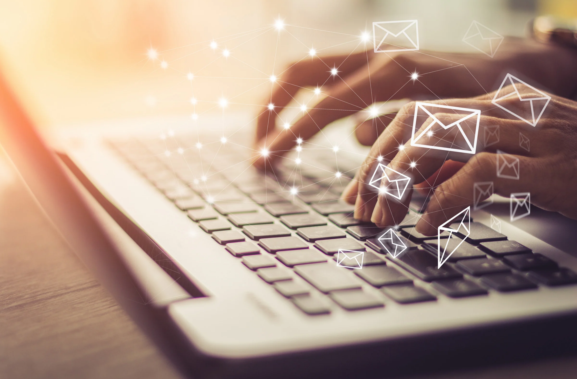 Hands typing on a laptop keyboard with floating email icons.