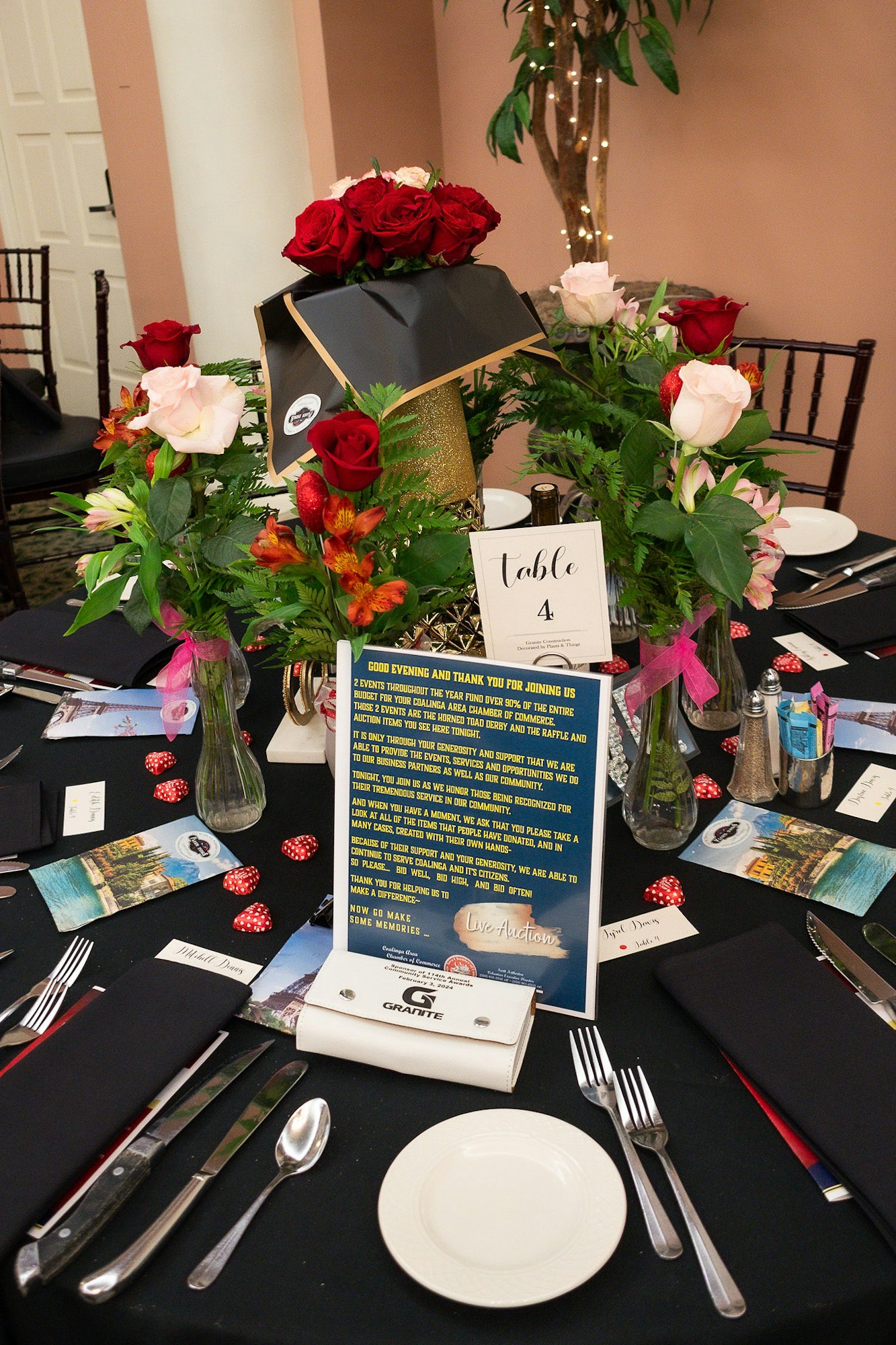 Elegantly set banquet table with flowers, place settings, and event literature.