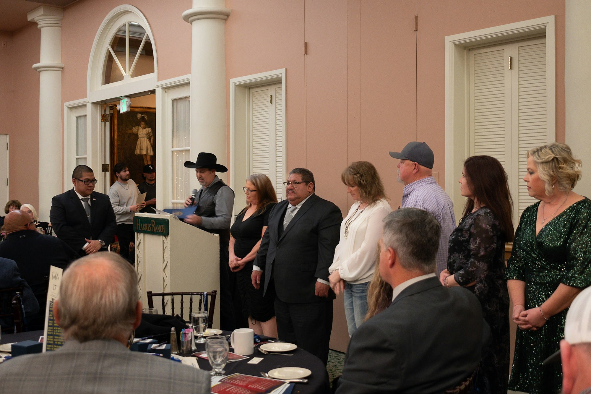 Group of people at an event with one man speaking at a podium.