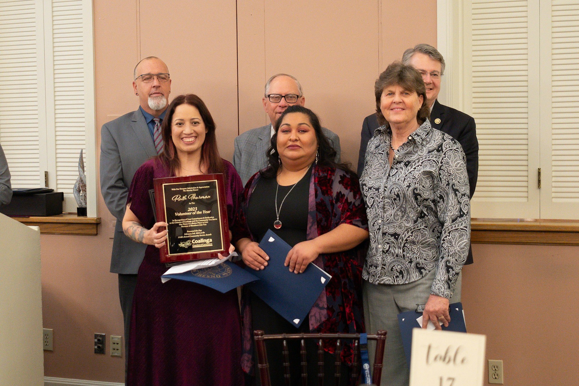 Group of people smiling, one holding a 'Volunteer of the Year' award plaque.
