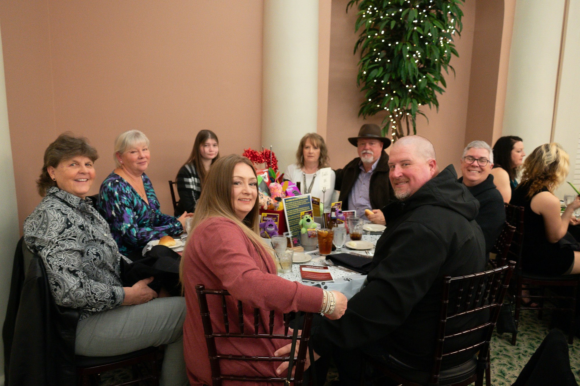 Group of people sitting around a table in a restaurant, smiling and enjoying a meal together.