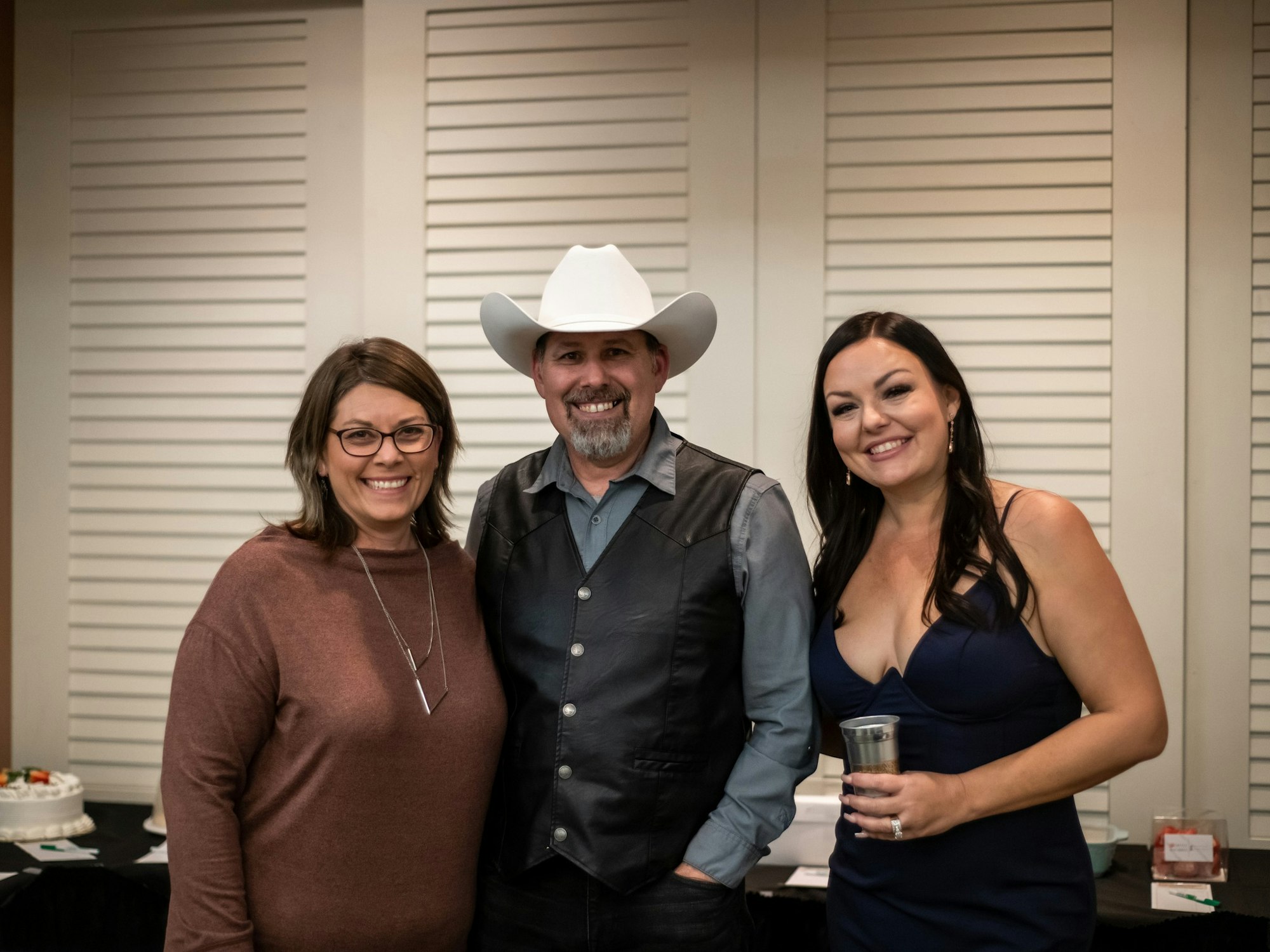 May contain: clothing, hat, adult, female, person, woman, accessories, glasses, jewelry, necklace, male, man, cup, ring, dress, pants, cowboy hat, and formal wear
