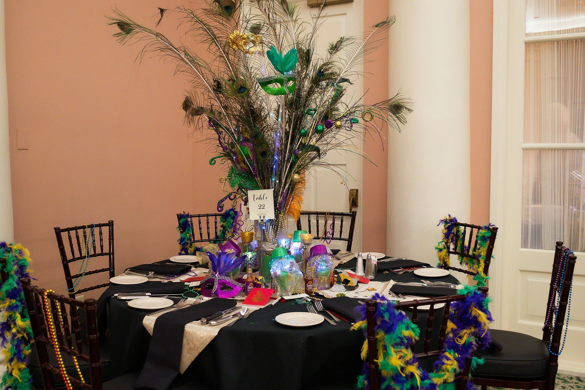 A festively decorated table with Mardi Gras beads, masks, and feathers, set for a themed event or celebration.