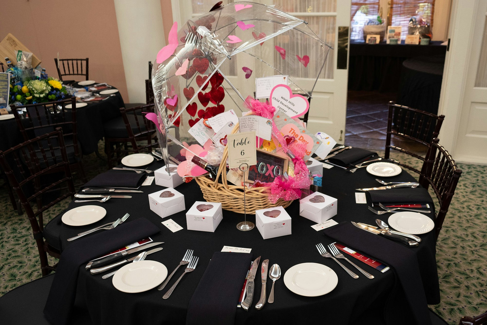 A decorated table set for an event with a centerpiece featuring hearts and gifts, likely a celebratory occasion.