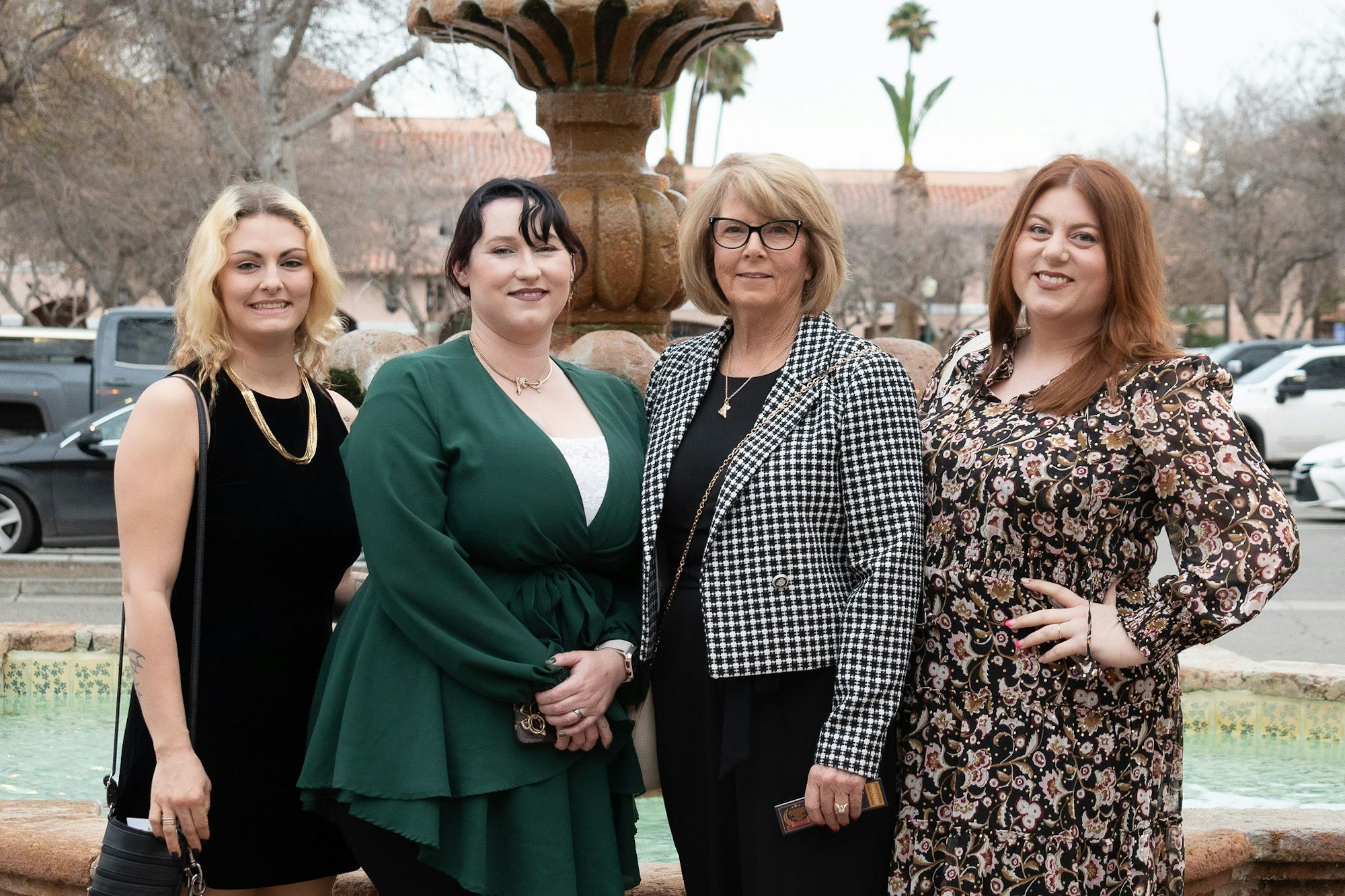 Four women posing in front of a fountain.