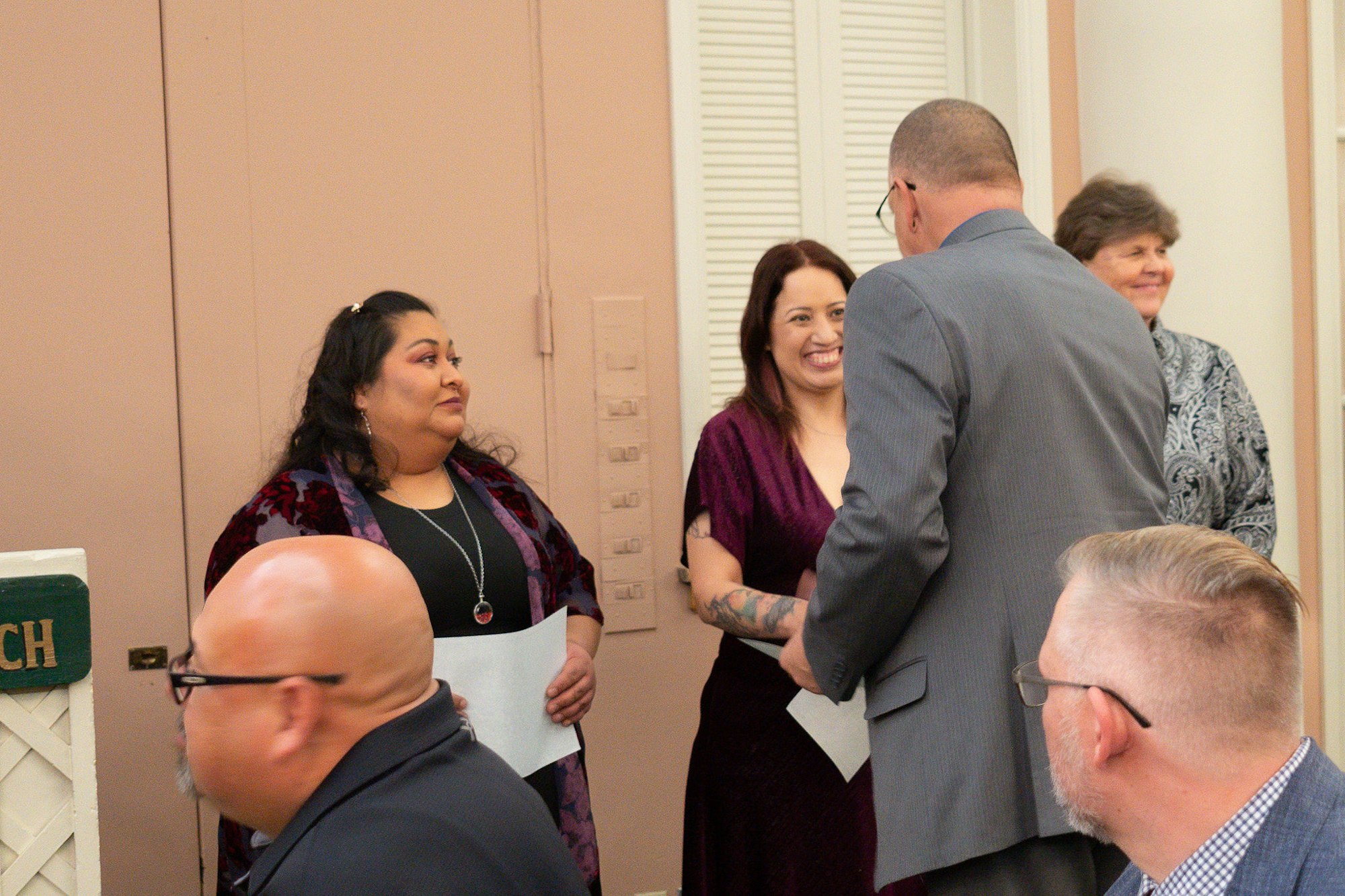 People gathered indoors, smiling and conversing, possibly at a social event.