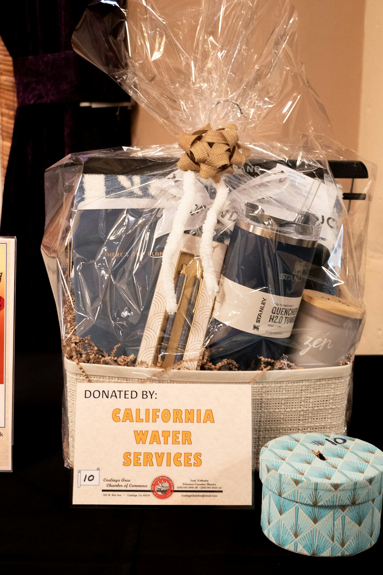 A gift basket with various items, wrapped in clear plastic and a sign indicating it was donated by California Water Services.