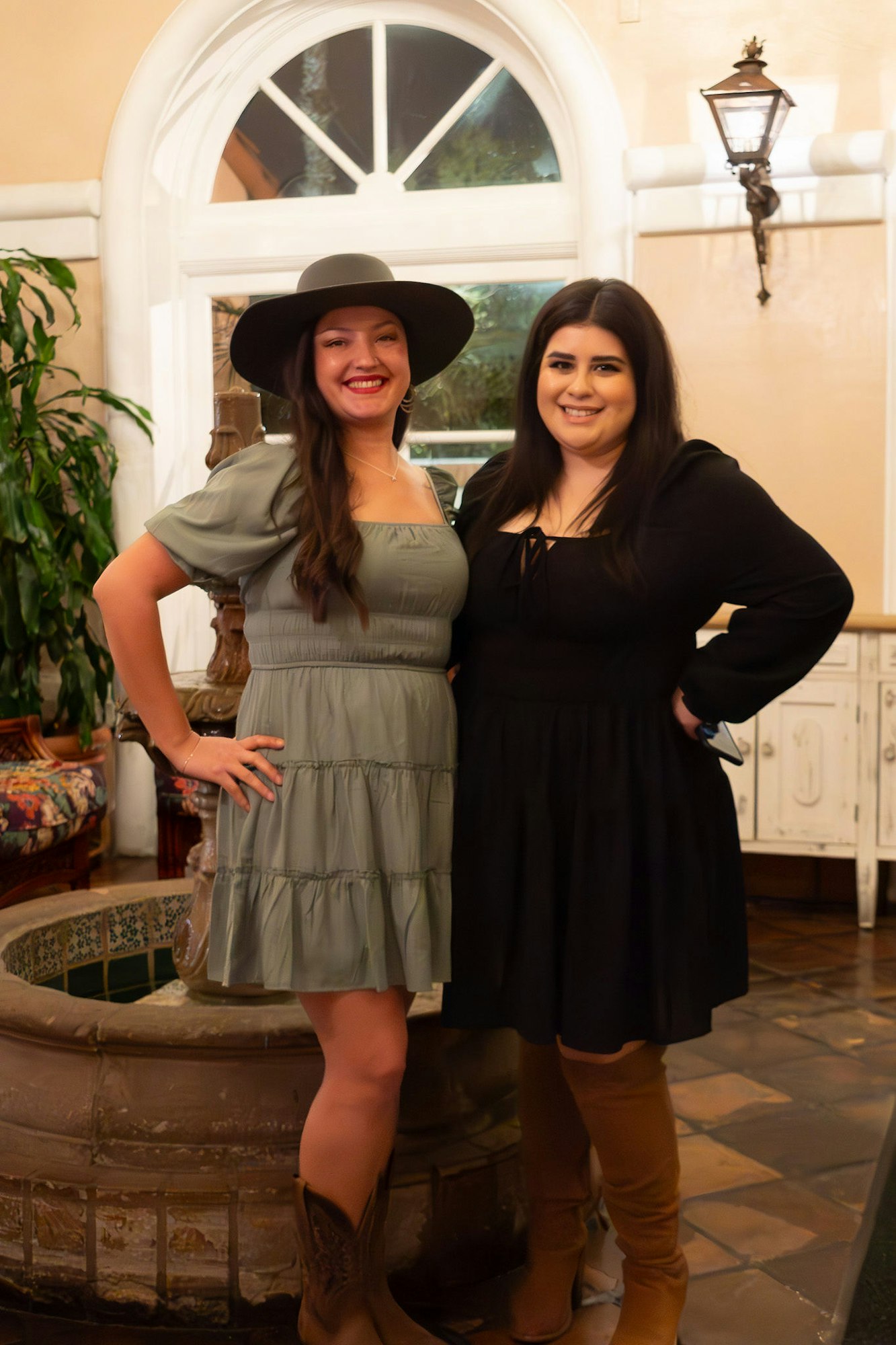 Two smiling women posing in an indoor setting with elegant decor.