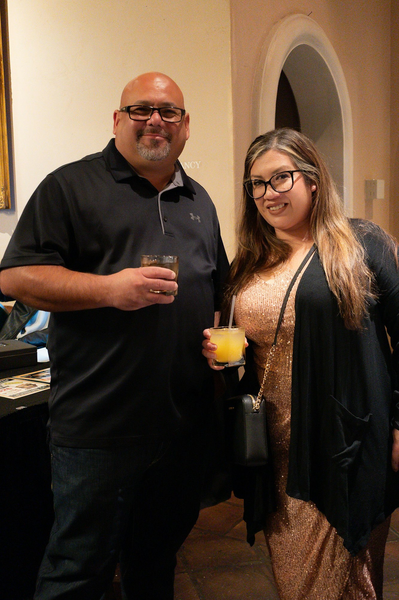 A man and a woman holding drinks at an indoor event.