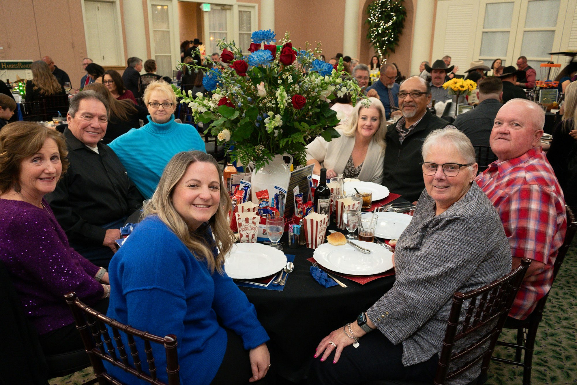 Group of people seated around a decorated table at an event, smiling for the camera.