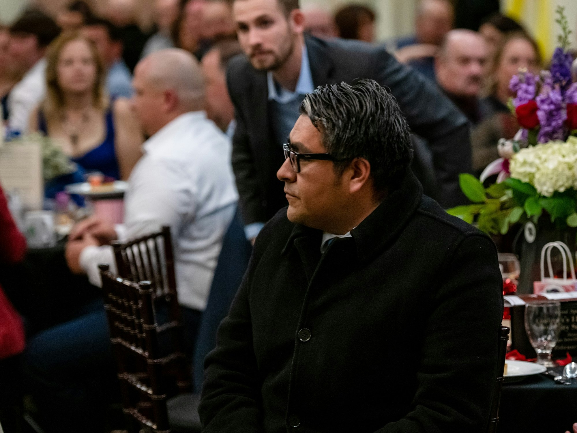May contain: flower, flower arrangement, plant, flower bouquet, adult, male, man, person, indoors, restaurant, accessories, glasses, plate, bag, and handbag