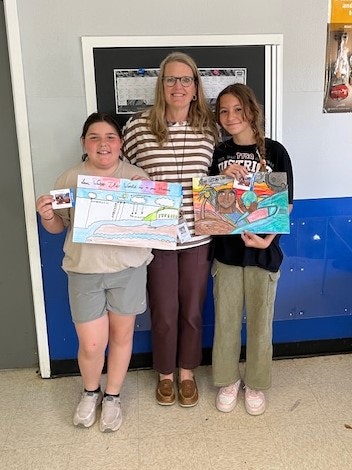 Three people smiling; two holding colorful drawings.