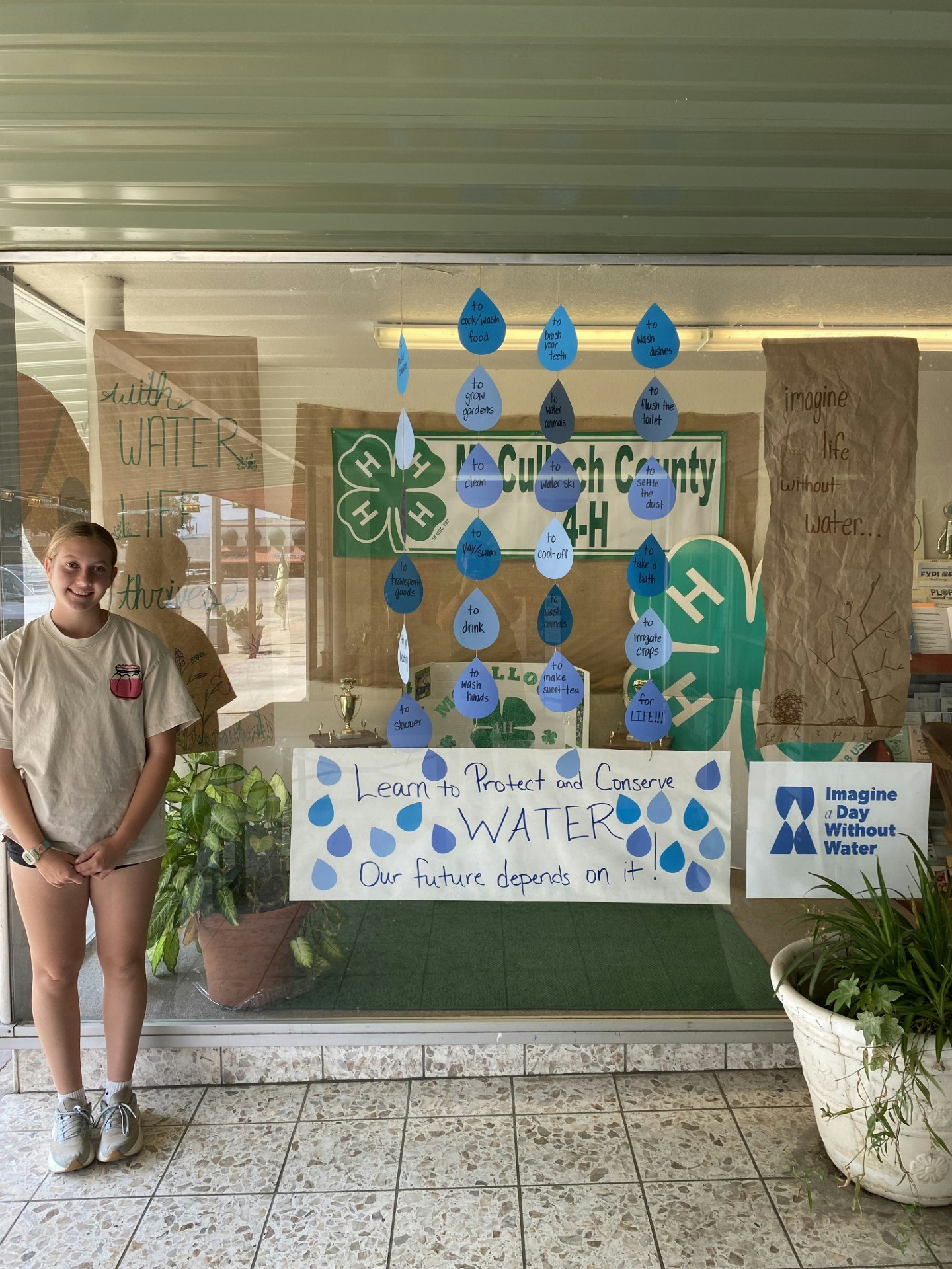 A person stands by a water conservation display with signs and posters promoting water protection and conservation.