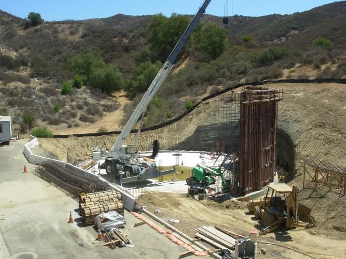 Construction site with a crane, machinery, and building materials in a hilly area.
