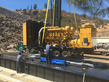 Industrial equipment being set up outdoors by two workers.