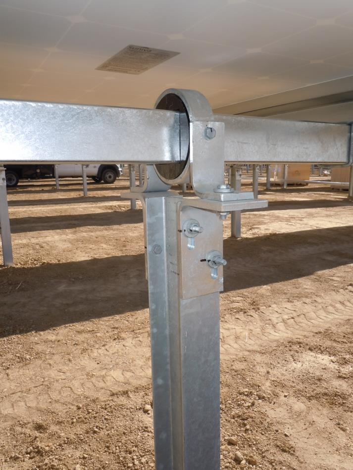 Metal support structure with bolts, possibly part of a solar panel installation, on a dirt ground.