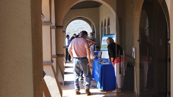 People attending a table in a hallway with a "Welcome" sign on a blue cloth.