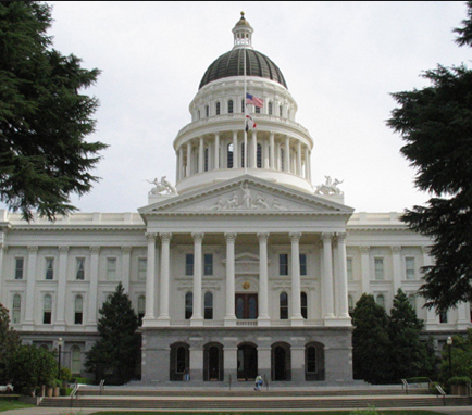 A large, classical-style government building with a prominent dome and columns, surrounded by trees.