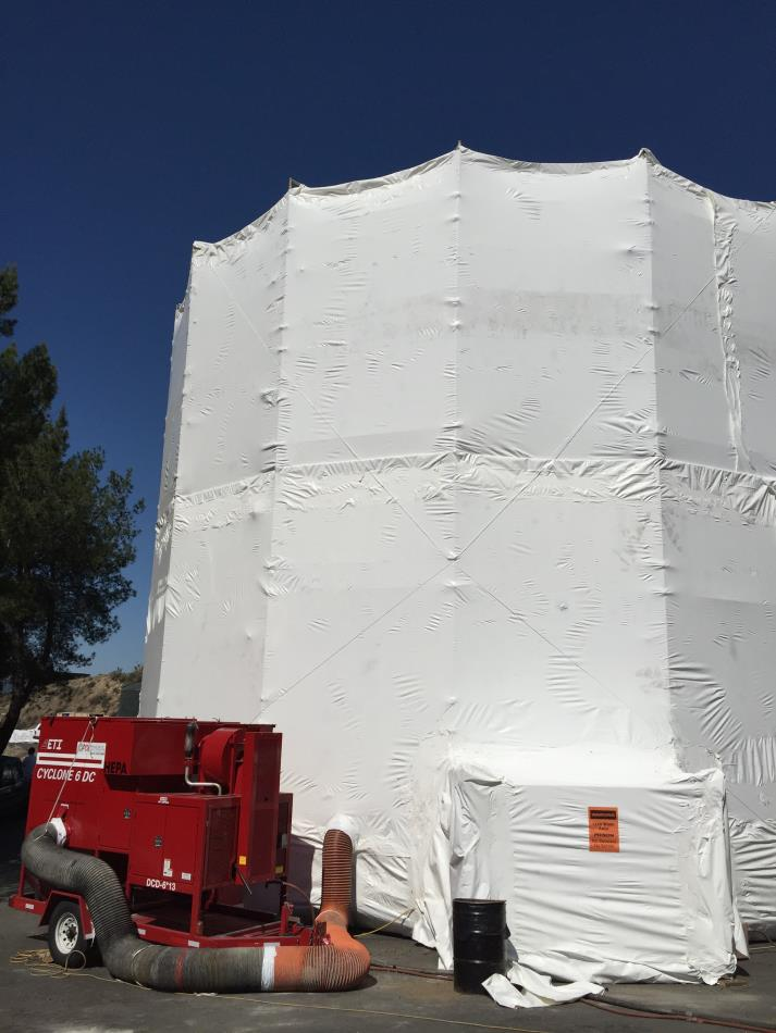 A large white tent structure with a red industrial machine and hoses attached to it.
