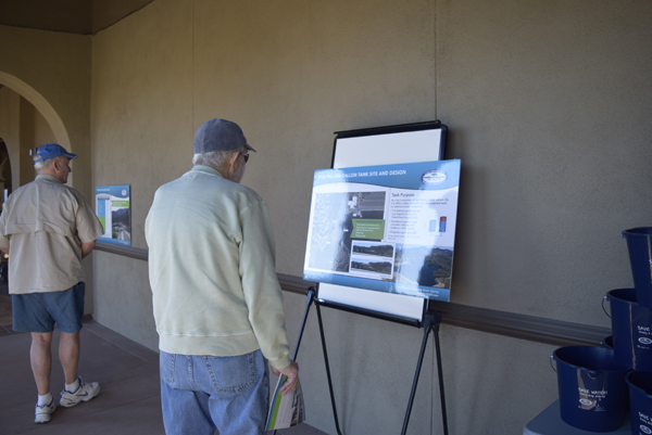 Two people observing informational displays on stands in an indoor setting.