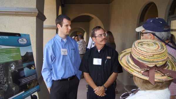 Several people are conversing near an informational poster, possibly at a professional or educational event.