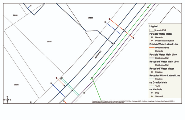 Map with water lines, meters, hydrants, manholes; labeled streets and parcels; legend detailing line and meter types.
