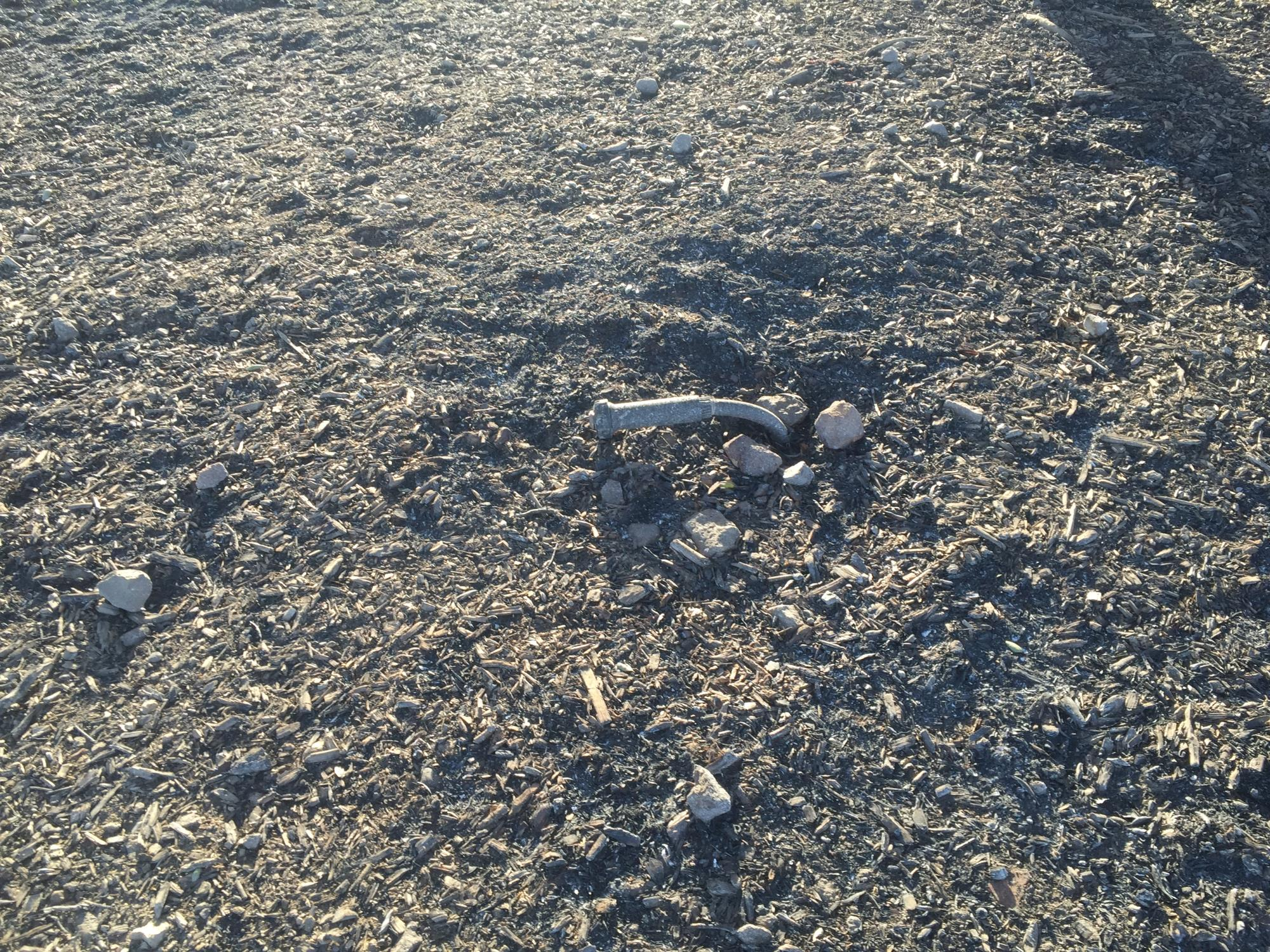 A dry, rocky ground with scattered stones and a metal pipe sticking out.