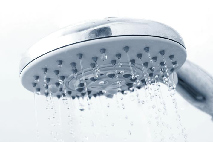 A shower head with water flowing from its nozzles.