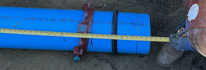 The image shows a blue pipe being measured with a tape measure, indicating installation or construction work.