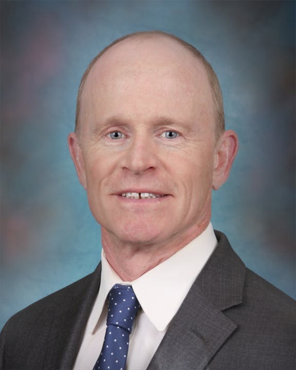 A man in a suit and tie with a blue background.