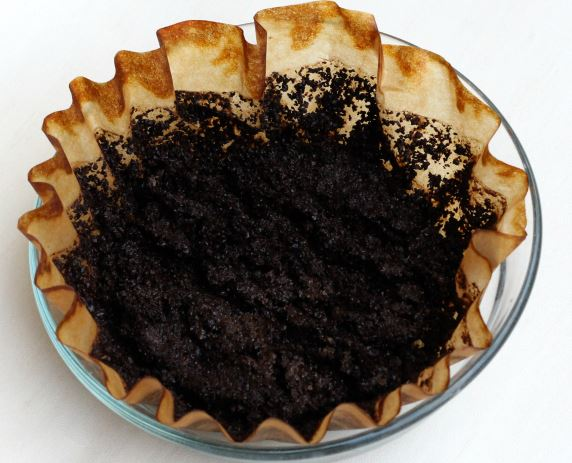 Used coffee grounds in a coffee filter inside a glass bowl.