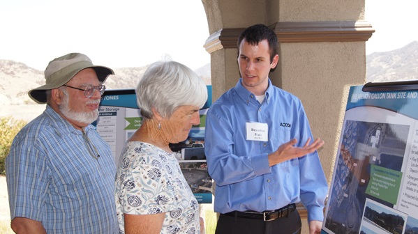 Three people discussing information on display boards outdoors.