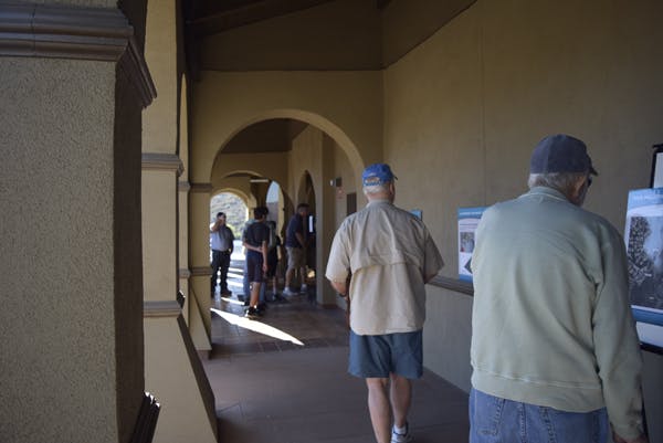 People in a hallway looking at display boards, with arches and sunlight streaming in.