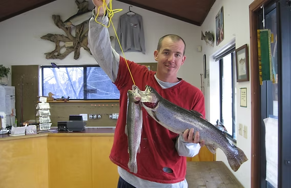 A person holding two large fish inside a room with fishing decor.