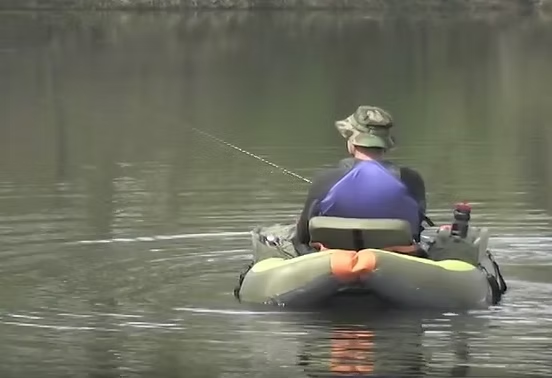 Person fishing from a kayak on a calm lake.