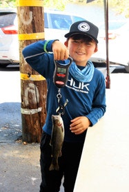 A smiling person holding a fish on a scale.