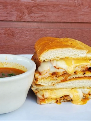 A grilled cheese sandwich stacked next to a bowl of tomato soup.