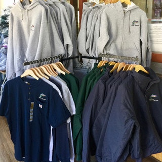 A display of gray hoodies, navy and green shirts, and dark jackets hanging on a rack.
